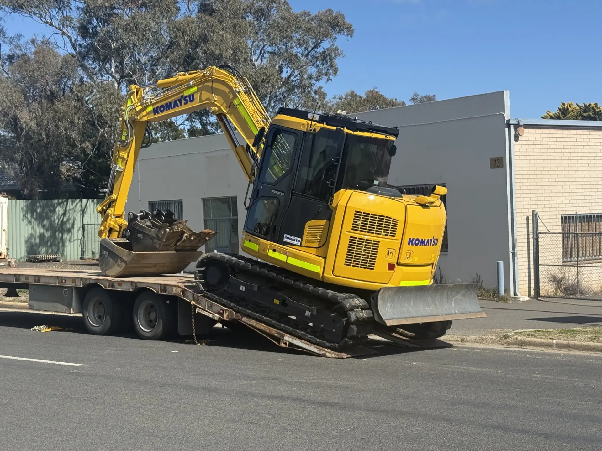 Mini excavator loaded on a flatbed, roadside